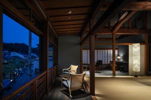 a room with a balcony with two chairs and a table at Kobayashiya -Kinosaki Onsen- in Toyooka