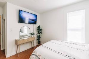 a white bedroom with a bed and a mirror at Bright, chic & spacious in the heart of St. Paul by Summit-University with porch and swing chairs in Saint Paul