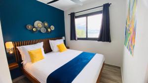 sypialnia z łóżkiem z żółtymi poduszkami i oknem w obiekcie BLUE VELVET na Nosy Be
