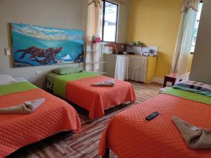 Habitación con 3 camas con sábanas naranjas y verdes en Mí oficina en Puerto Ayora