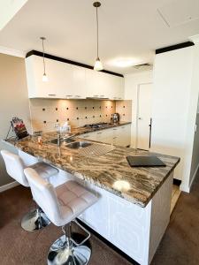 a kitchen with a counter with a sink and two bar stools at Rockingham Waterfront at Nautilus in Rockingham
