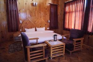 1 dormitorio con 1 cama, 2 sillas y mesa en The Vintage Inn by suman cottage, en Manali