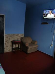 a living room with a couch and a tv on a blue wall at Hotel 24/7 in Comayagua