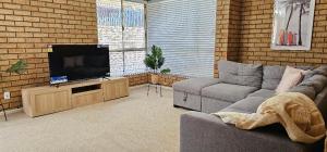 een woonkamer met een bank en een flatscreen-tv bij Peaceful House in Perth