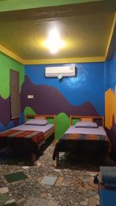 a room with two beds and a blue and green wall at sunrise seasports in Iboih