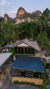 a building with a blue roof in front of a mountain at Nahm Khao Sok in Khao Sok