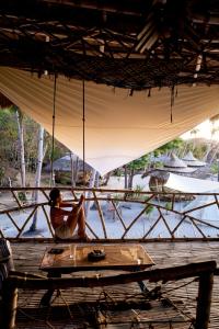 a woman sitting on a porch swing looking at the water at Dryft Darocotan Island in El Nido