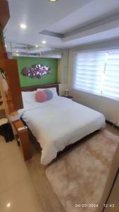 a bedroom with a large white bed with a green wall at Relaxing Studio at Morgan Suites walking distance Venice Piazza T219P in Manila