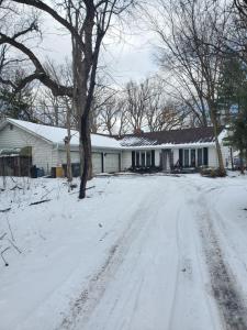 a snow covered road in front of a house at A Stay In The Woods in Steger