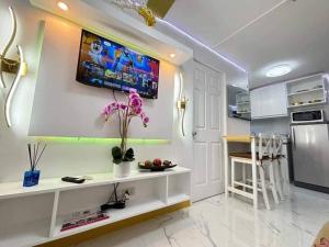 een woonkamer met een televisie aan de muur bij Hacienda Balai 9-2L in Manilla