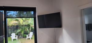 a flat screen tv on a wall with two chairs at Kiwiblue in Kerikeri