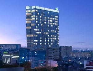 فندق Santika Premiere Hayam Wuruk Jakarta في جاكرتا: مبنى طويل مع أضواء على مدينة