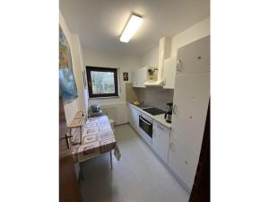 eine kleine Küche mit weißen Schränken und einem Tisch in der Unterkunft Yvonne Modern retreat in Titisee-Neustadt