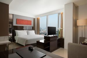 a bedroom with a bed and a desk with a television at Hotel Santika Premiere Hayam Wuruk Jakarta in Jakarta