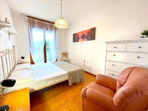 a bedroom with a bed and a chair and a dresser at Inviting apartment by the beach in Porto Santa Margherita di Caorle