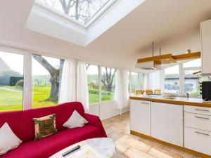 a kitchen with a red couch in a room with windows at Walnut Modern retreat in Hödingen