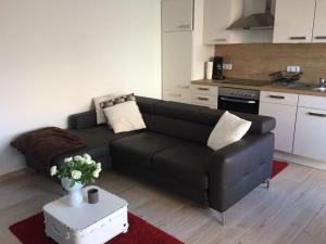 ein Wohnzimmer mit einem schwarzen Sofa und einer Küche in der Unterkunft Ostbake Modern retreat in Wangerooge