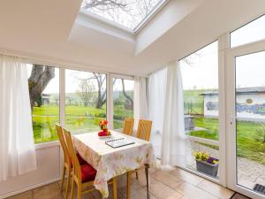 a dining room with a table and some windows at Walnut Modern retreat in Hödingen