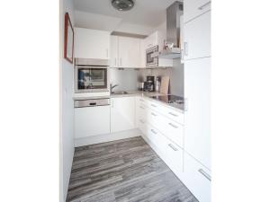 cocina blanca con armarios blancos y suelo de madera en 14 Böhler Brise Modern retreat, en Sankt Peter-Ording