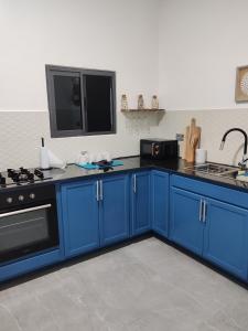 eine Küche mit blauen Schränken und einem TV an der Wand in der Unterkunft Le Leo Lodge in Lomé