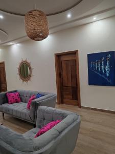 ein Wohnzimmer mit 2 Sofas und rosa Kissen in der Unterkunft Le Leo Lodge in Lomé