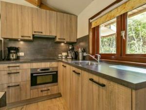 a kitchen with wooden cabinets and a large window at Huijsmansverhuur Type C Comfort Plus Prinsenhof 51 in Ouddorp