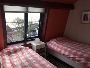 een slaapkamer met 2 aparte bedden en een raam bij Aan de Kade Modern retreat in Enkhuizen