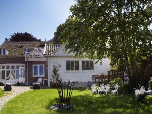 una casa con un patio con sillas y un árbol en Makkinje-Labes 2, en Oostwoud