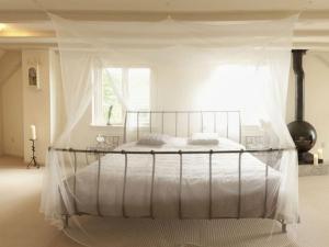 Una cama blanca con dosel en un dormitorio en Makkinje-Labes 2, en Oostwoud