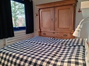 a bedroom with a checkered bed with a dresser and a window at The Blue House Modern retreat in Wangerooge