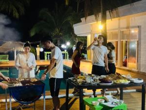 grupa ludzi stojących przy stole z jedzeniem w obiekcie Amor Resort Koh Rong w mieście Koh Rong
