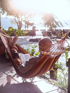 a man sitting in a hammock reading a book at Cat Ba SOL Beach in Cat Ba