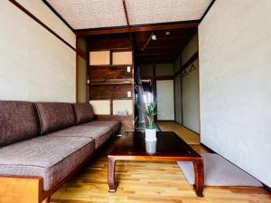 a living room with a couch and a coffee table at Guesthouse Azumaya in Matsumoto