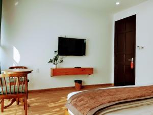 1 dormitorio con 1 cama y TV en la pared en PHƯƠNG ĐÔNG HUẾ HOMESTAY, en Hue