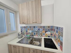 cocina con fregadero y azulejos en la pared en La Bomboniera, en Capri