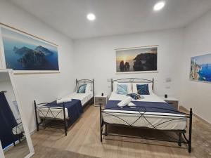 a bedroom with two beds and paintings on the wall at La Bomboniera in Capri