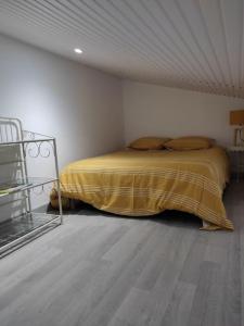 - une chambre avec un lit et une couverture jaune dans l'établissement MONTALIVET STUDIO MEZZANINE, à Vendays-Montalivet