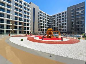 un parque infantil frente a un gran edificio de apartamentos en Stylish Studio in New residence with pool and gym en Dubái