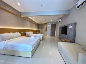 a hotel room with two beds and a flat screen tv at The Shore by MD Staycation in Kota Kinabalu