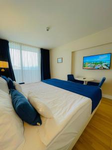 a bedroom with a large white bed with blue pillows at Luxury Batumi Hotel in Batumi