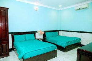 a blue room with two beds and a table at Mi Linh Hotel in Nha Trang