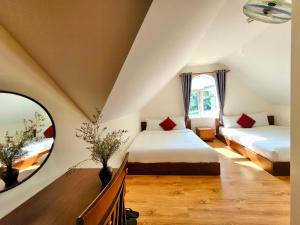 a attic bedroom with two beds and a mirror at Carnival Villa in Da Lat
