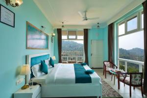 a bedroom with a large bed with blue walls at The Crosswoods Three in Mukteswar