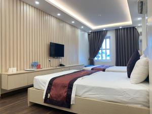 1 dormitorio con 2 camas y TV de pantalla plana en Khách Sạn Tom’s en Thái Nguyên