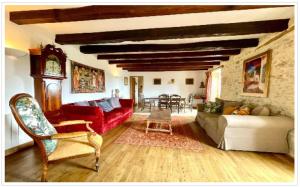 a living room with a red couch and a clock at Le Coin Tranquille in La Roque-Gageac
