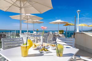 a white table with drinks and food on a beach at Sky Pool Hotel Sole Garda in Garda