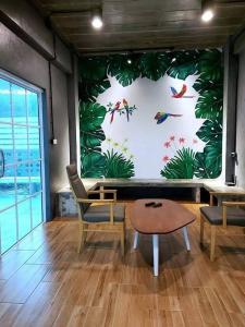 a room with a large wall with birds and plants at Mango tree cafe de’ villa in Mae Pim