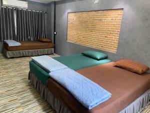 twee bedden in een kamer met een bakstenen muur bij Mango tree cafe de’ villa in Mae Pim