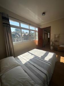 a bedroom with a large bed with a large window at Riverside 2bed cozy apartment in La Trinidad