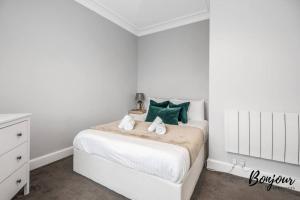 a white bedroom with a white bed with green pillows at Lilas Suite Abbeyhill - 1BR-1BA 5 Mins to Meadowbank Shopping by Bonjour Residences Edinburgh in Edinburgh